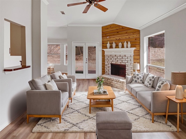 living area with wood finished floors, visible vents, lofted ceiling, french doors, and a brick fireplace