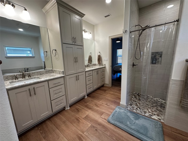 full bathroom with visible vents, wood finished floors, vanity, and a tile shower