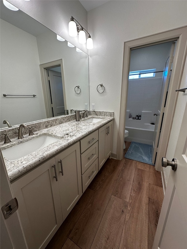 full bath featuring double vanity, toilet, wood finished floors, and a sink