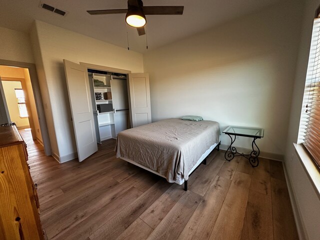 bedroom featuring ceiling fan, visible vents, baseboards, and wood finished floors