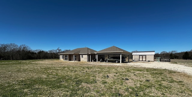 back of house with a carport, a lawn, and an outdoor structure