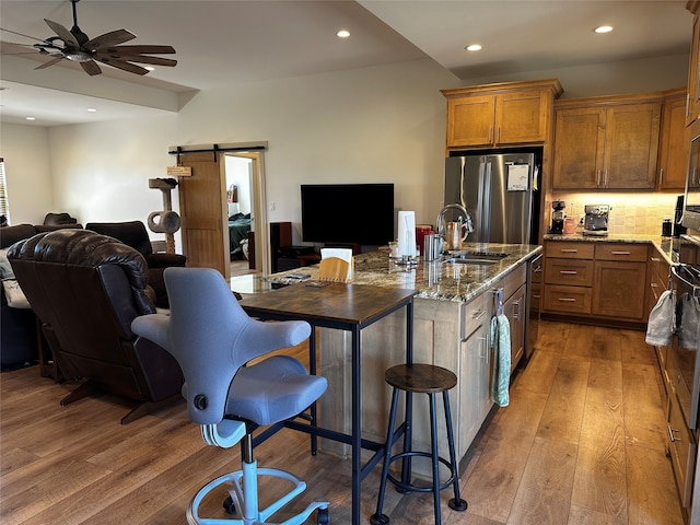 kitchen featuring open floor plan, freestanding refrigerator, a barn door, and a sink