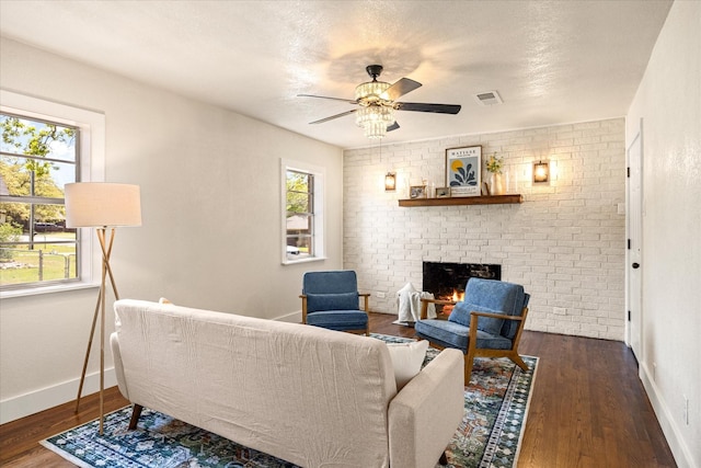 living area featuring a fireplace, ceiling fan, a healthy amount of sunlight, and wood finished floors