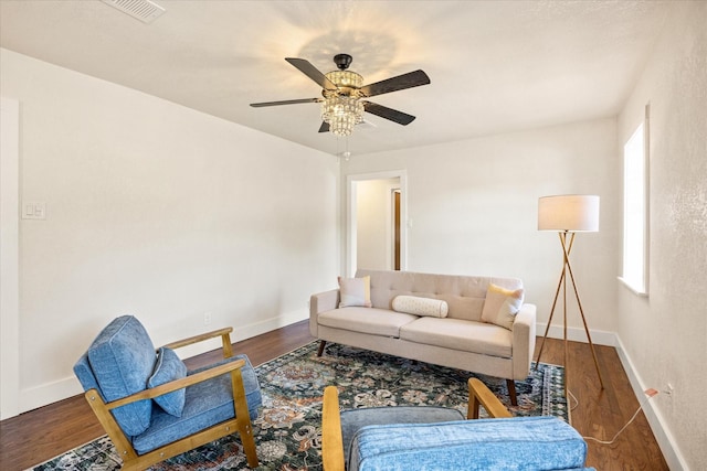 living area featuring a ceiling fan, baseboards, visible vents, and wood finished floors