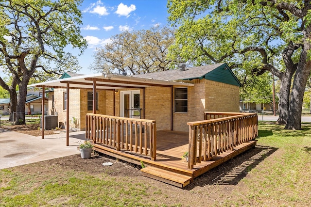 rear view of house with a deck, french doors, brick siding, a yard, and central AC unit