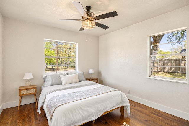 bedroom featuring baseboards, multiple windows, ceiling fan, and wood finished floors