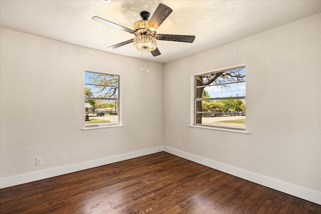 spare room with baseboards, ceiling fan, and dark wood-style floors