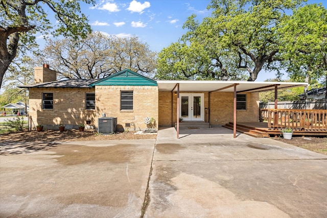 back of house with french doors, a chimney, fence, central air condition unit, and brick siding