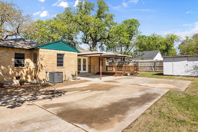 back of house featuring central air condition unit, brick siding, french doors, and fence