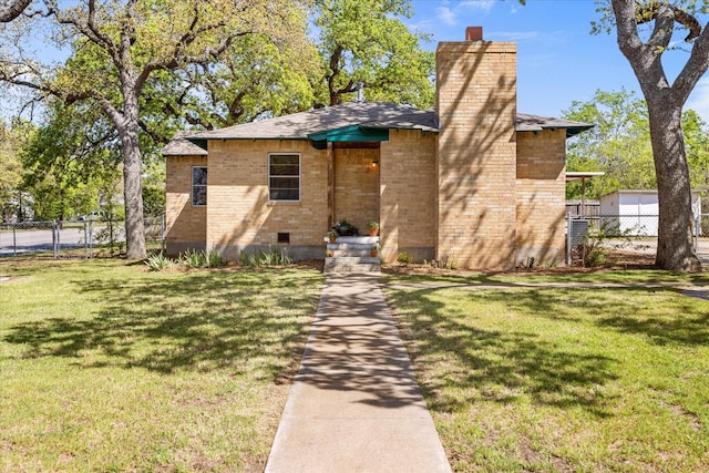 view of front of property with a chimney, brick siding, a front lawn, and fence