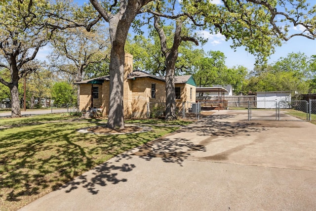 view of home's exterior featuring driveway, brick siding, fence, cooling unit, and a gate