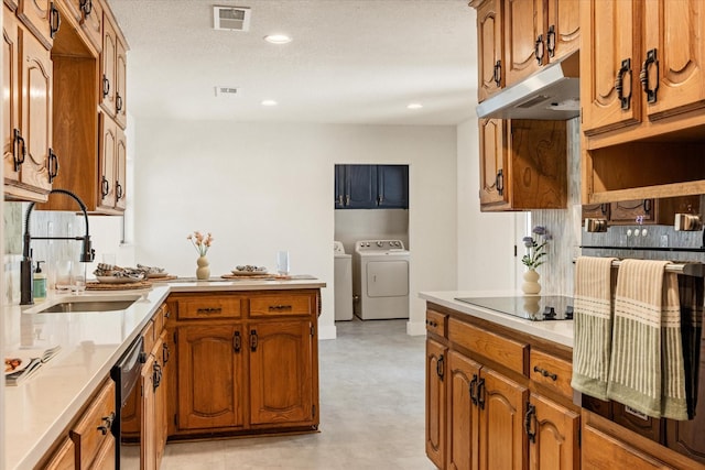 kitchen with under cabinet range hood, visible vents, a sink, washing machine and clothes dryer, and black appliances