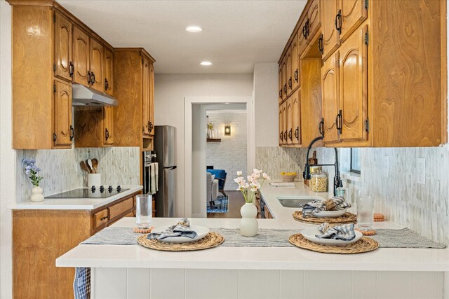 201 E 3rd St, Weatherford, TX 76086 - kitchen featuring black electric cooktop, under cabinet range hood, a peninsula, light countertops, and tasteful backsplash