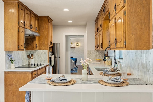 kitchen with black electric cooktop, light countertops, a peninsula, and tasteful backsplash