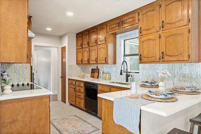 kitchen with a sink, a peninsula, brown cabinetry, and black appliances