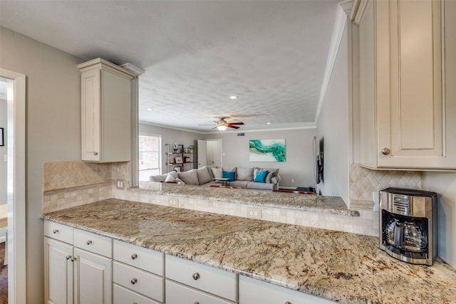 kitchen with tasteful backsplash, light stone countertops, open floor plan, and ceiling fan