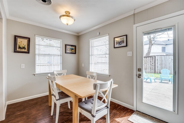 dining space featuring a healthy amount of sunlight, wood finished floors, baseboards, and ornamental molding