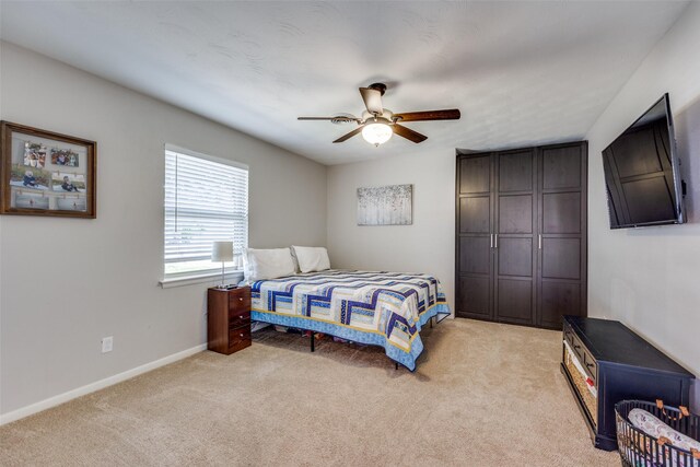 bedroom with light colored carpet, baseboards, and ceiling fan