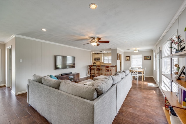 living room with dark wood-type flooring, crown molding, and baseboards