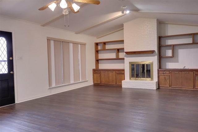 unfurnished living room with a brick fireplace, lofted ceiling with beams, a ceiling fan, and dark wood-style flooring