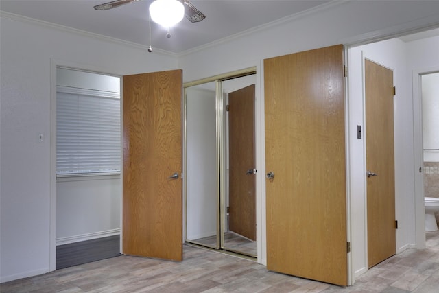 unfurnished bedroom with two closets, crown molding, baseboards, and wood finished floors