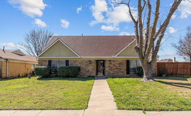 view of front facade featuring a front lawn, fence, brick siding, and a shingled roof