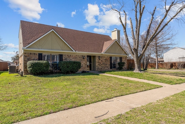 view of front facade featuring a shingled roof, a front yard, and a chimney