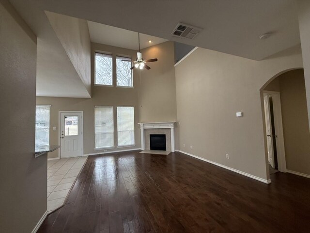 unfurnished living room with visible vents, wood finished floors, a premium fireplace, baseboards, and ceiling fan