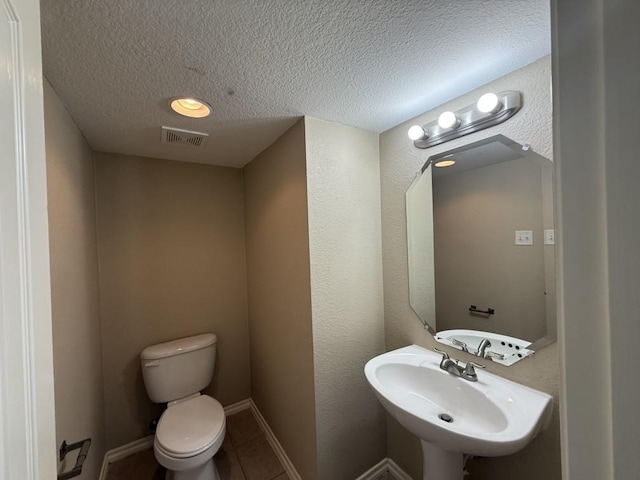 bathroom featuring visible vents, a sink, a textured ceiling, tile patterned floors, and toilet