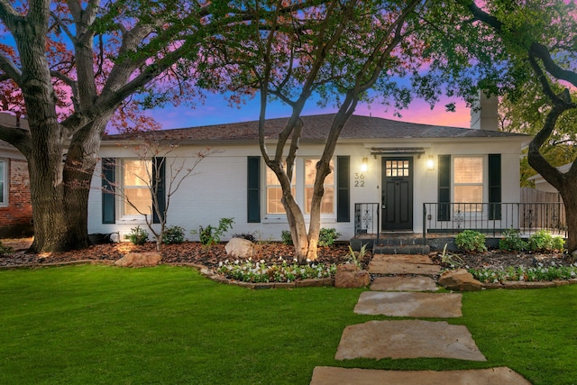 single story home with a porch, brick siding, a chimney, and a front yard