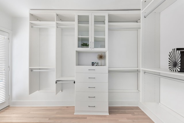 walk in closet with light wood-style floors