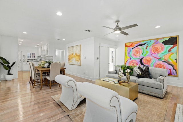 living area with light wood finished floors, visible vents, recessed lighting, and baseboards