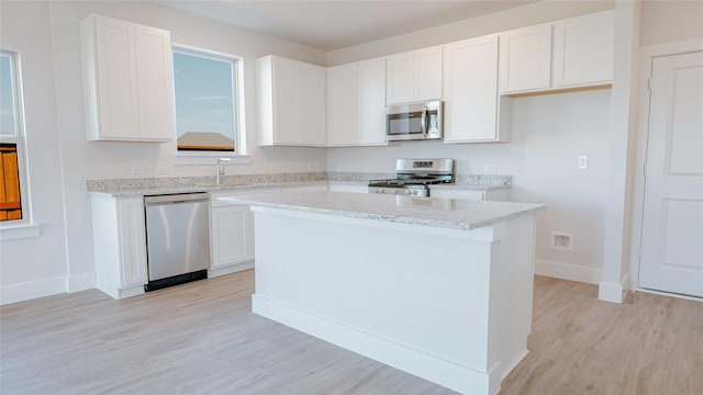 kitchen featuring white cabinetry, light stone countertops, appliances with stainless steel finishes, and a kitchen island