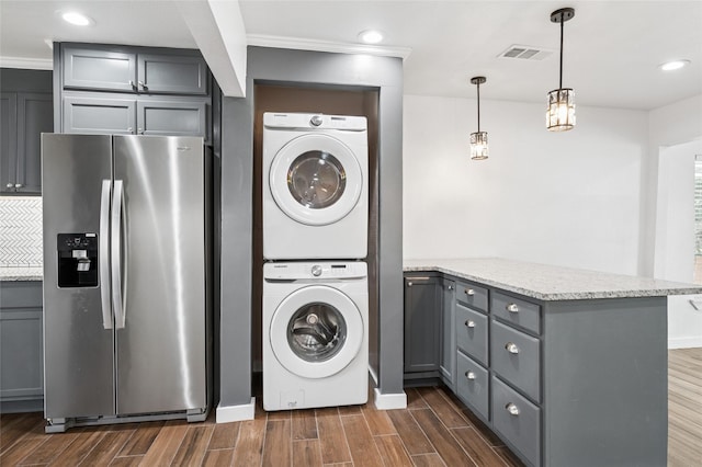 washroom with stacked washer / dryer, wood finish floors, and visible vents