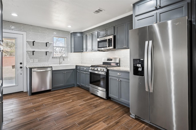 kitchen featuring visible vents, gray cabinetry, dark wood-style floors, stainless steel appliances, and decorative backsplash