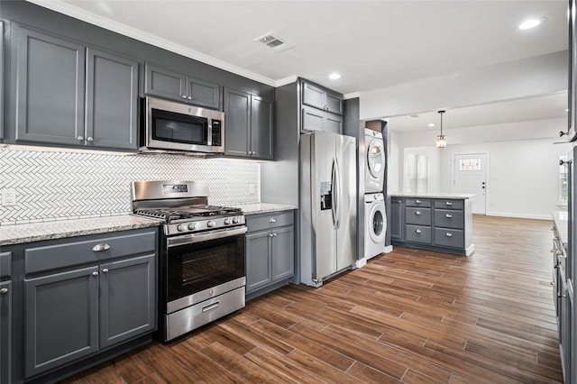 kitchen with visible vents, stacked washer and dryer, tasteful backsplash, dark wood-style floors, and appliances with stainless steel finishes