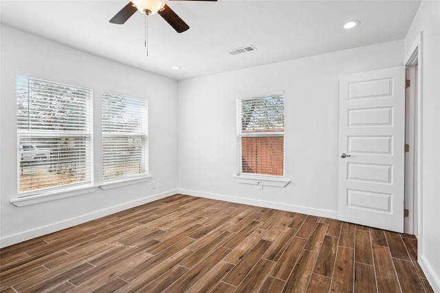 unfurnished room featuring plenty of natural light, baseboards, visible vents, and dark wood-style flooring