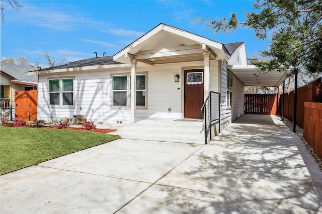 view of front facade with driveway, fence, a front yard, crawl space, and a carport