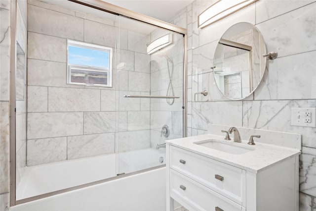 full bath with bath / shower combo with glass door, tile walls, and vanity