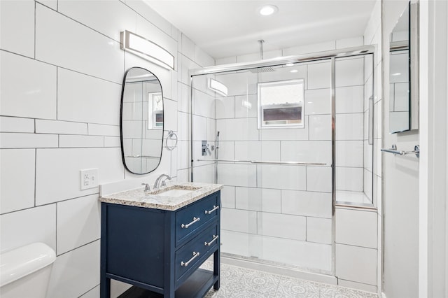 full bath with vanity, toilet, tile walls, and a shower stall