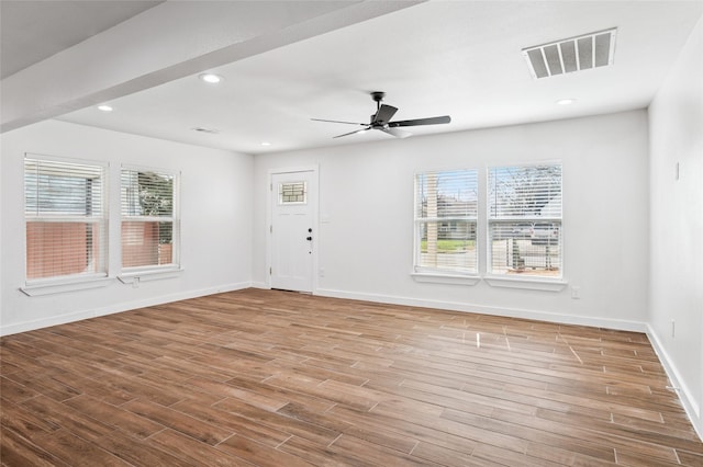 unfurnished room featuring visible vents, plenty of natural light, and wood finished floors