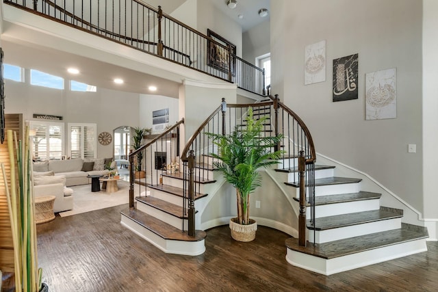 stairway featuring a high ceiling, baseboards, and wood finished floors