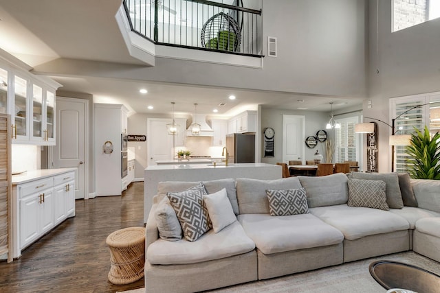 living room featuring recessed lighting, an inviting chandelier, a towering ceiling, and dark wood-style flooring