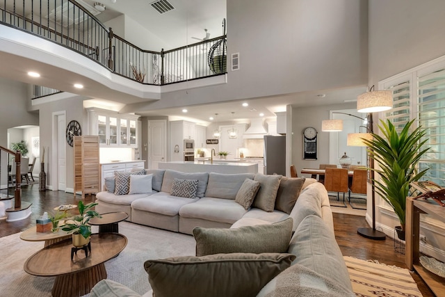 living area featuring arched walkways, visible vents, stairs, and dark wood-style flooring