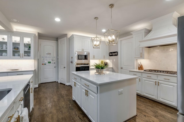 kitchen with a center island, dark wood-type flooring, stainless steel appliances, custom exhaust hood, and white cabinetry