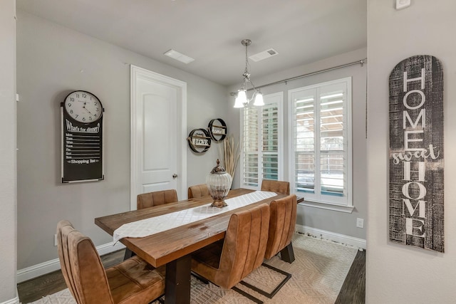 dining area with visible vents, an inviting chandelier, baseboards, and wood finished floors