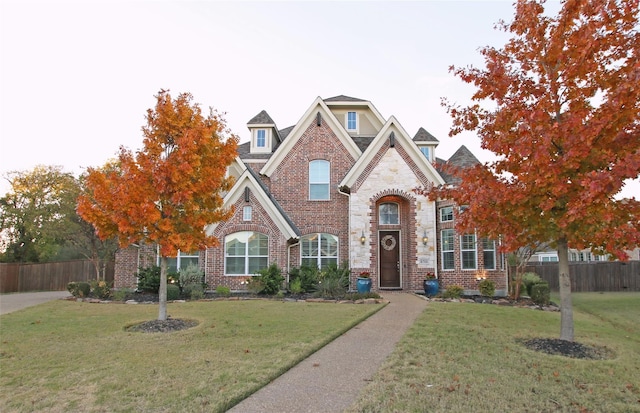 view of front of house with brick siding, a front yard, and fence