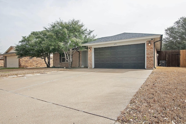 single story home featuring central AC unit, fence, an attached garage, concrete driveway, and brick siding