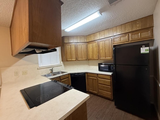 kitchen with brown cabinets, black appliances, a sink, a textured ceiling, and light countertops