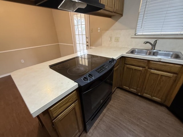 kitchen featuring a peninsula, a sink, light countertops, exhaust hood, and black electric range oven